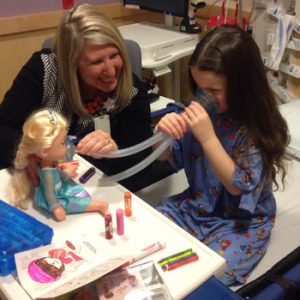 Child life specialist and patient use a doll to learn about procedure.