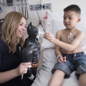 Child life specialist and patient play with Batman doll to learn about procedure.